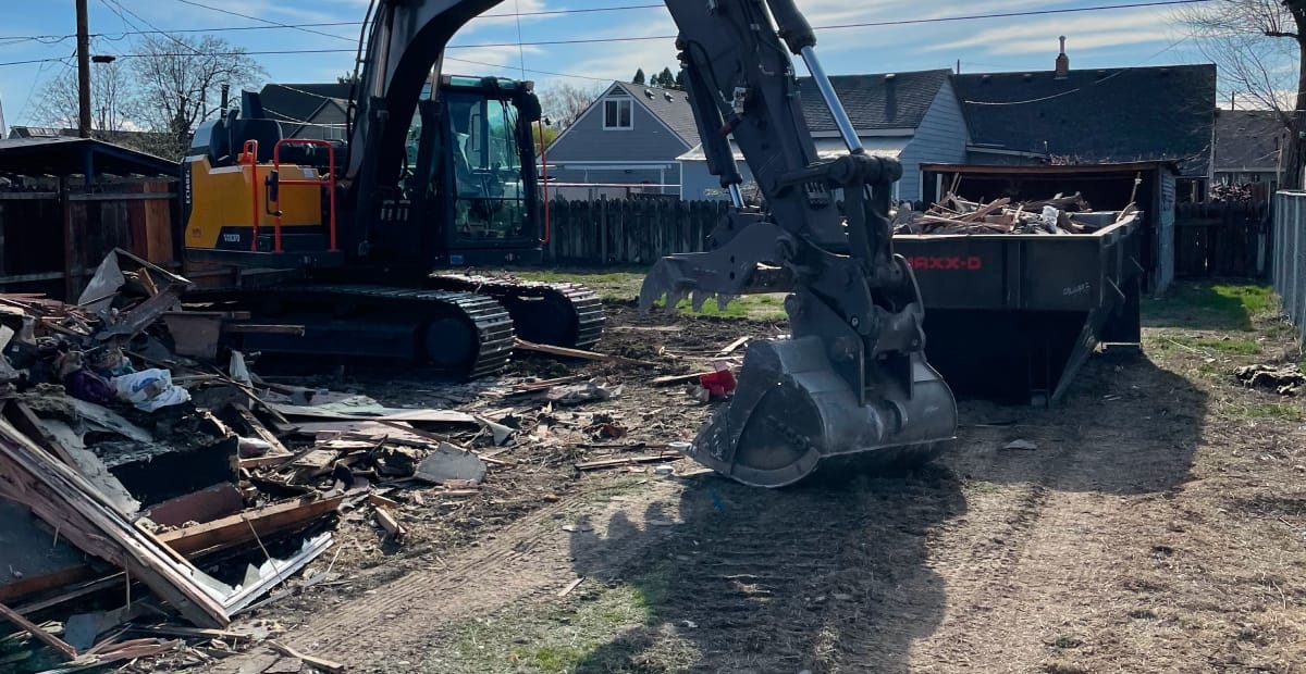 Excavator clearing debris from demolition site.