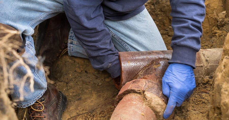 Worker repairing underground water pipe.