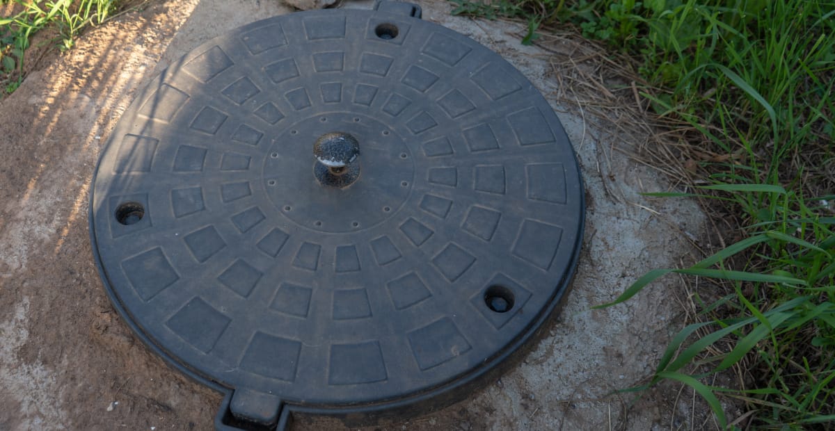 Round manhole cover on grassy ground.