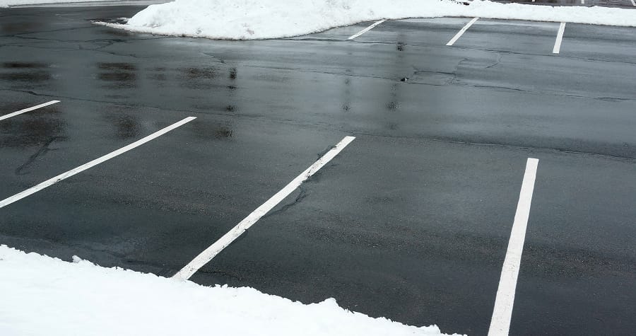 Snowy empty parking lot with clear spaces